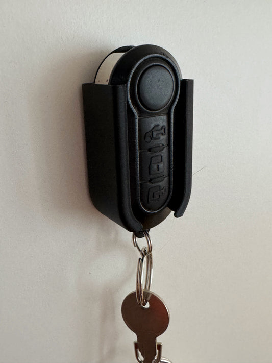 schwarzer Schlüsselhalter mit Schlüssel, der Fahrzeugschlüssel wird sicher ghalten, der kleine Schlüssel hängt nach unten.